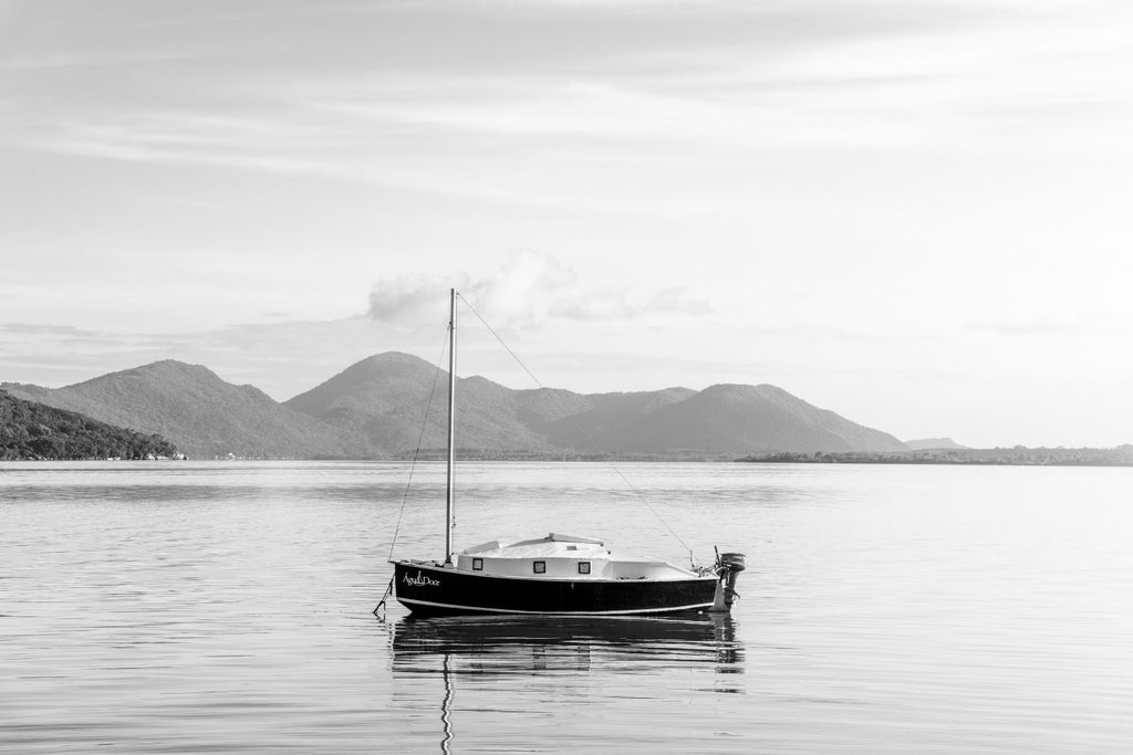 Un barco no por do sol em preto e blanco